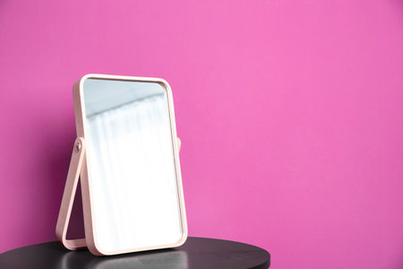 Stylish mirror on table near color wallの写真素材
