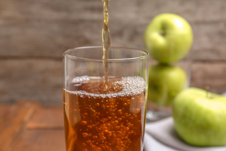 Pouring fresh apple juice into glass on wooden background, closeupの写真素材
