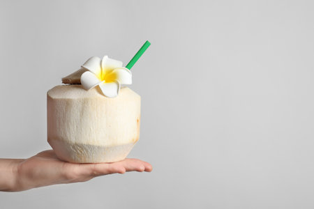 Woman with fresh coconut drink in nut on light background, closeupの写真素材