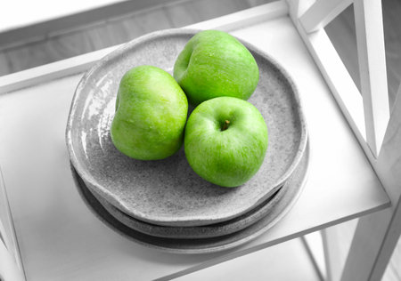 Plate with fresh green apples on shelfの写真素材