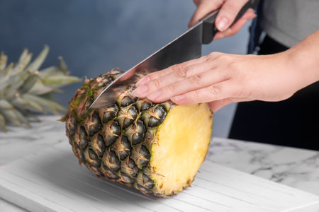 Woman cutting fresh pineapple on wooden boardの写真素材