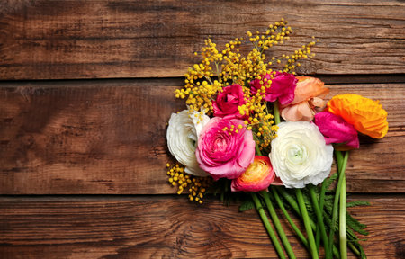 Beautiful ranunculus and mimosa flowers on wooden backgroundの写真素材