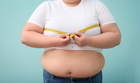 Overweight woman with measuring tape on color background