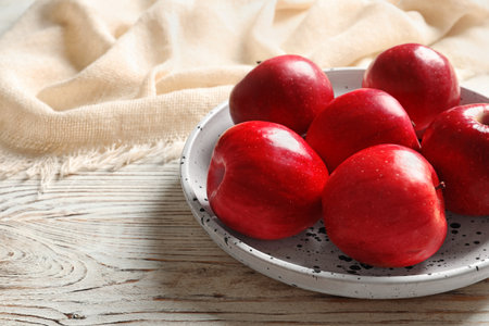 Plate with ripe red apples on wooden backgroundの写真素材