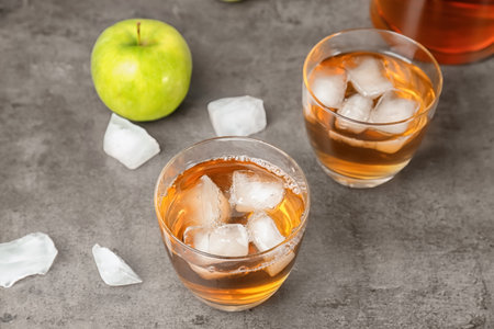 Glasses of apple juice with ice cubes on tableの写真素材