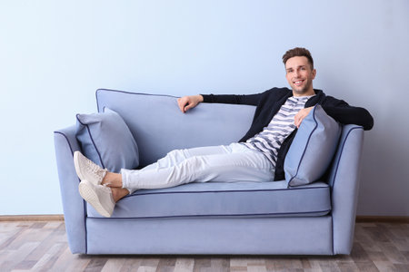 Handsome young man on sofa, indoorsの写真素材