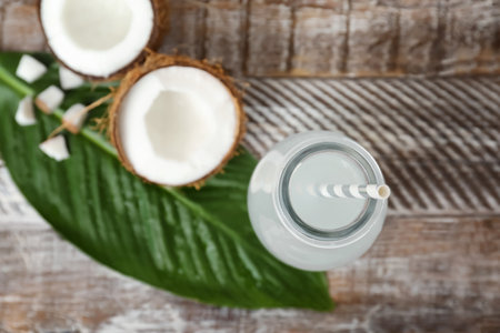 Bottle of coconut water and fresh nuts on wooden table, top viewの写真素材