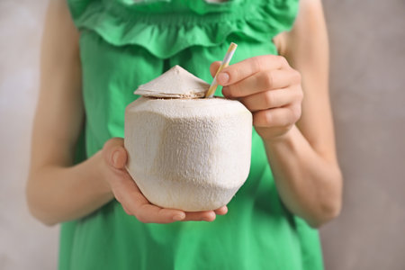 Woman with fresh coconut drink in nut on gray background, closeupの写真素材