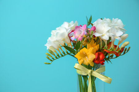 Glass vase with beautiful freesia on color backgroundの写真素材