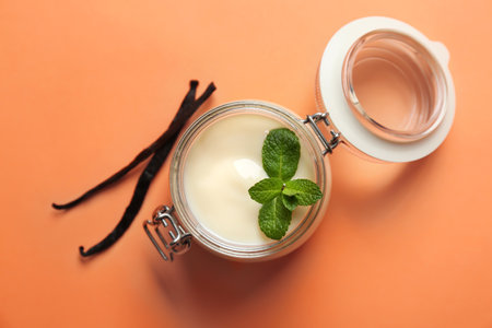 Jar with vanilla pudding, sticks and fresh mint on color backgroundの写真素材