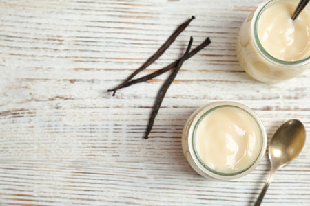 Jars with vanilla pudding and sticks on wooden backgroundの写真素材
