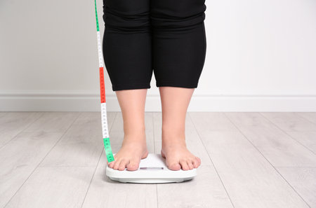Overweight woman using scales indoorsの写真素材