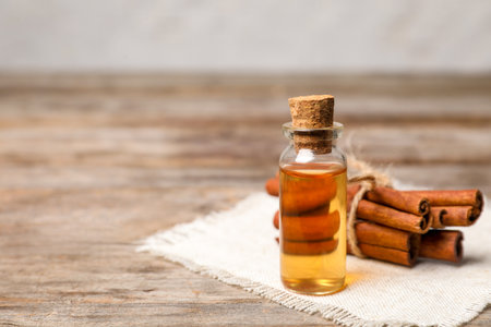 Bottle with cinnamon essential oil and sticks on wooden tableの写真素材