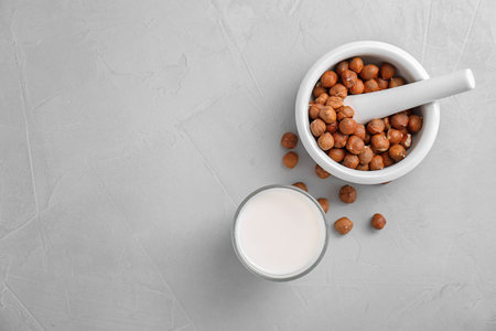 Glass with hazelnut milk and nuts in mortar on light background, top viewの写真素材