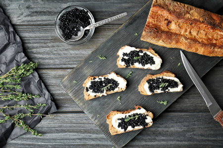 Sandwiches with black caviar and butter on wooden boardの写真素材