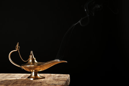 Aladdin magic lamp on table against black backgroundの写真素材