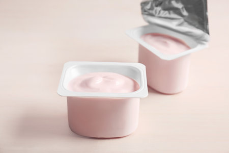 Plastic cups with yummy yogurt on wooden tableの写真素材