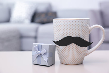 Cup with mustache and gift box on table. father's day celebrationの写真素材