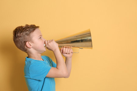 Cute little boy with megaphone on color backgroundの写真素材