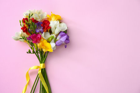 Beautiful freesia bouquet with ribbon on color backgroundの写真素材