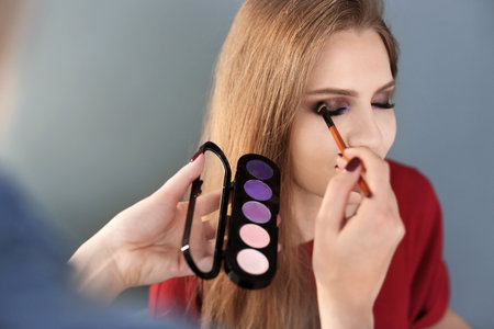 Professional makeup artist working with beautiful young woman in studioの写真素材