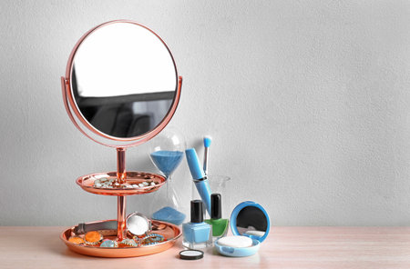 Modern mirror with makeup products and accessories on table near color wallの写真素材