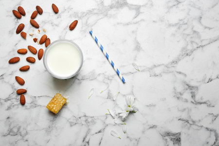 Glass with milk, nuts and honeycomb on light background, flat layの写真素材