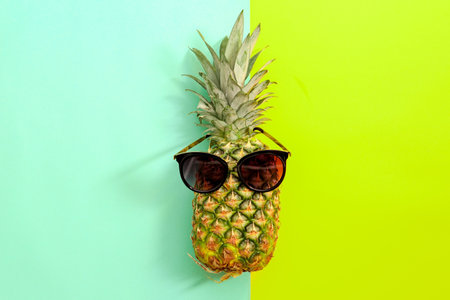 Fresh ripe pineapple with sunglasses on color background, top viewの写真素材