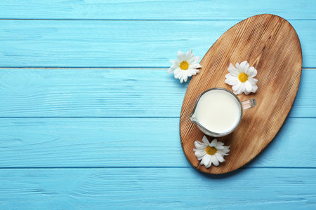 Jug with milk and flowers on wooden background, top viewの写真素材