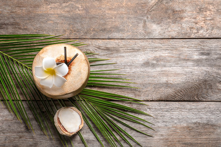 Beautiful composition with fresh green coconut and palm leaf on wooden backgroundの写真素材