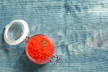 Glass jar with delicious red caviar on tableの写真素材