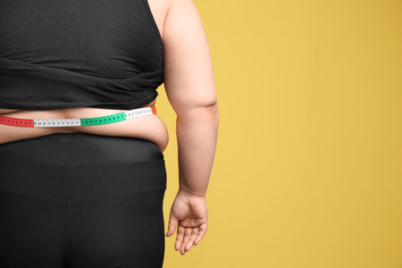 Overweight woman with measuring tape on color backgroundの写真素材