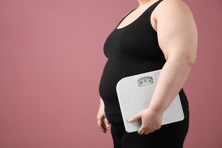 Overweight woman with scales on color backgroundの写真素材