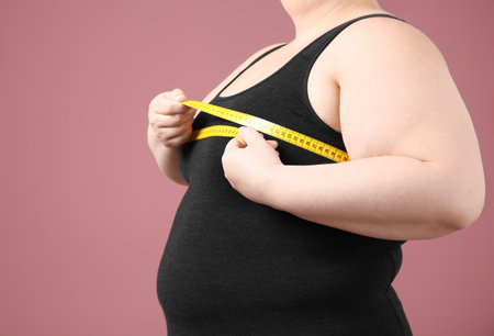 Overweight woman with measuring tape on color backgroundの写真素材