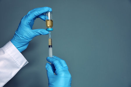 Doctor with syringe and medicine for vaccination on color backgroundの写真素材