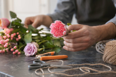Male florist creating beautiful bouquet at table, closeupの写真素材