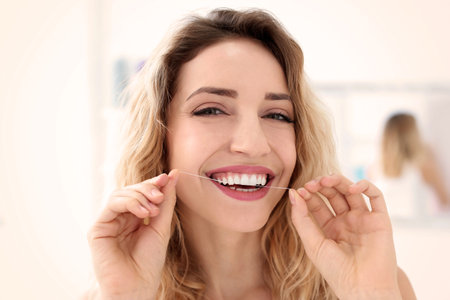 Young woman flossing her teeth indoors