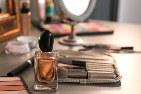 Bottle of perfume and makeup products on dressing table