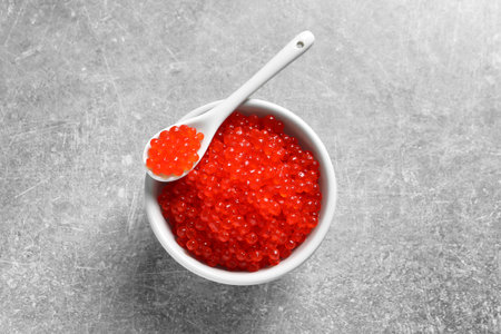 Ceramic bowl and spoon with delicious red caviar on tableの写真素材