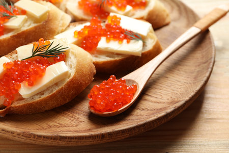 Delicious sandwiches and spoon with red caviar on wooden plate, closeupの写真素材