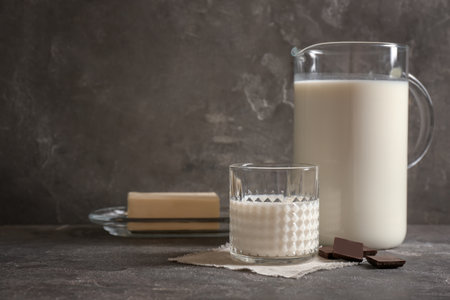 Glass and jug with milk on gray tableの写真素材