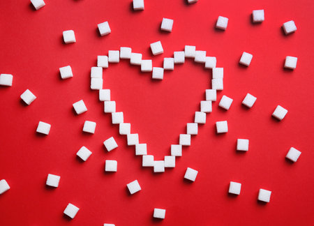 Heart shape made of refined sugar cubes on color background, top viewの写真素材