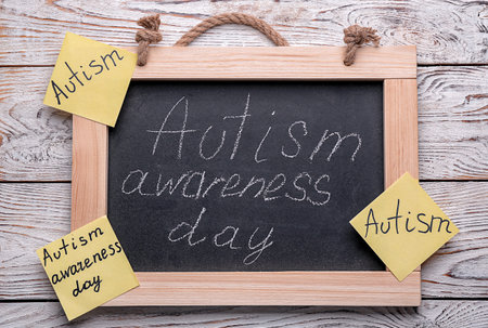 Chalkboard with phrase "Autism awareness day" on wooden backgroundの写真素材