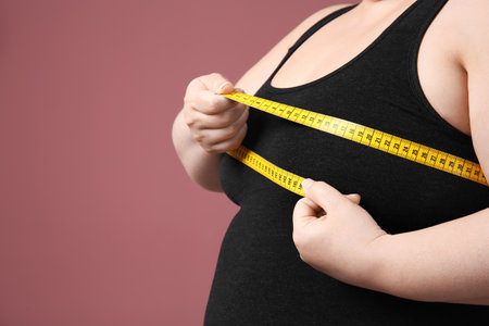 Overweight woman with measuring tape on color backgroundの写真素材