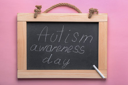 Chalkboard with phrase "Autism awareness day" on color backgroundの写真素材