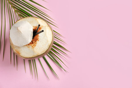 Fresh green coconut with drinking straws and palm leaf on color backgroundの写真素材