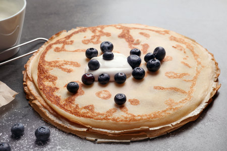 Thin pancakes with cream and berries on tableの写真素材