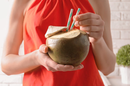 Young woman with fresh coconut cocktail on blurred background, closeupの写真素材