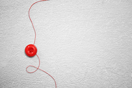 Thread and button on light background. tailoring accessories