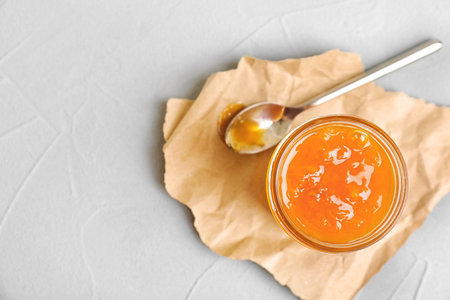 Jar and spoon with sweet jam on textured backgroundの写真素材